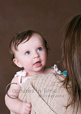 toddler in her mother's arms on brown backdrop