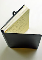 a black leather notebook with a yellow page