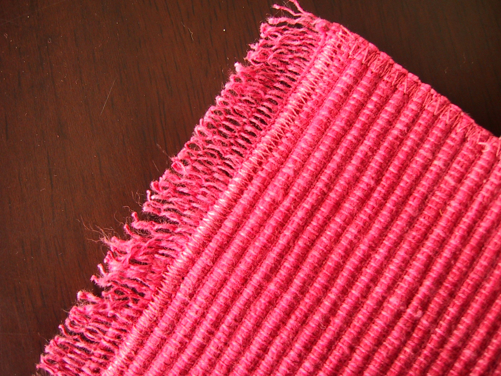 Modern dolls' house miniature floor rug made out of a pink woven place mat.