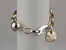 picture of Twisted Silver bracelet with chain links and a charm that says twisted on a gray background