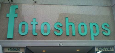 Storefront sign that reads Fotoshops in green sans serif condensed letters