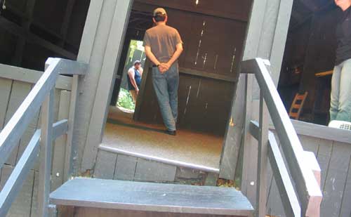 Photo of a man walking on an angle across the floor of the shack