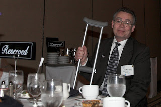 Jim McClurg, seated at a dinner table with crutch