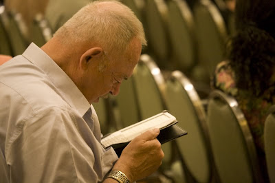 Man reading a Kindle ebook reader, holding it close to his eyes.