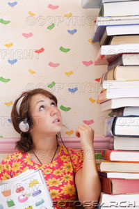 [woman-wearing-headphones-looking-at-pile-of-books-~-200338921-001.jpg]