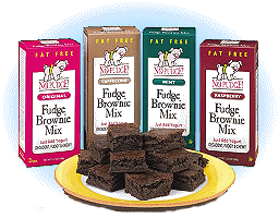 picture of four boxes of No Pudge Fat Free Brownie mix with a plate of brownies beneath the boxes, all on a blue background
